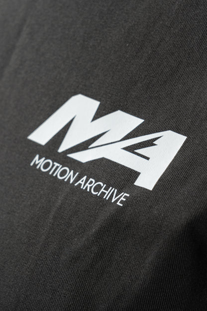 Close-up of a black t-shirt featuring a white printed logo with the text 'M4 MOTION ARCHIVE'.