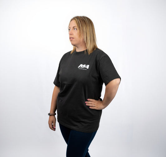 A woman modeling a black short-sleeve t-shirt with a white 'MA Motorsports' logo on the left chest, set against a plain white studio background.